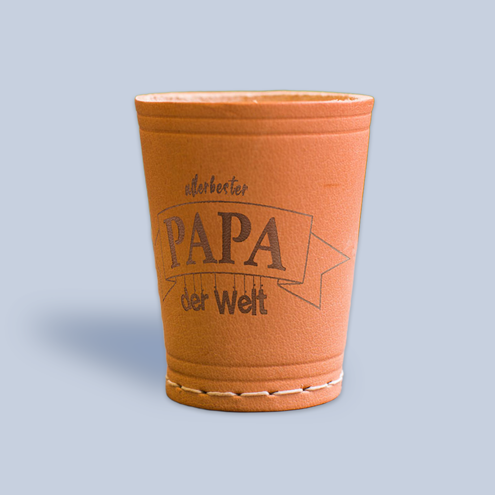 Würfelbecher mit Gravur Motiv "Allerbester Papa der Welt" auf hellblauen Hintergrund mit leichtem Schattenfall 