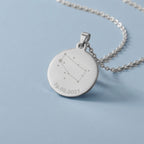 Kettenanhänger mit Sternzeichengravur und Datum an einer silbernen Kette hängend