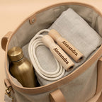 Braunes Springseil mit gravierten Holzgriffen auf beige Stofftasche, personalisiertes Sportzubehör, ideales Geschenk mit individuellem Namen.